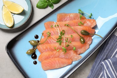 Photo of Delicious salmon carpaccio served on light grey table, flat lay