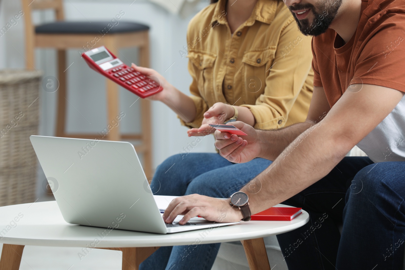 Photo of Young couple discussing family budget at table indoors, closeup