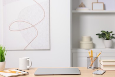 Photo of Home office. Laptop, cup and stationery on wooden desk indoors. Space for text