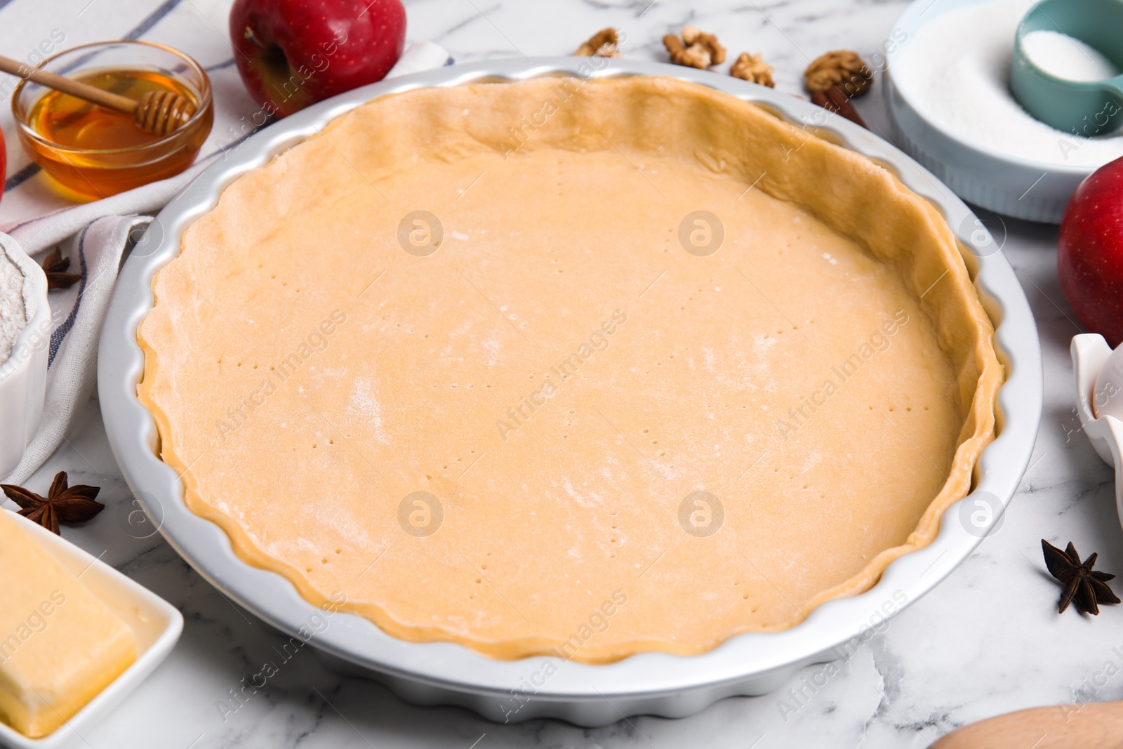 Photo of Raw dough for traditional English apple pie on white marble table, closeup