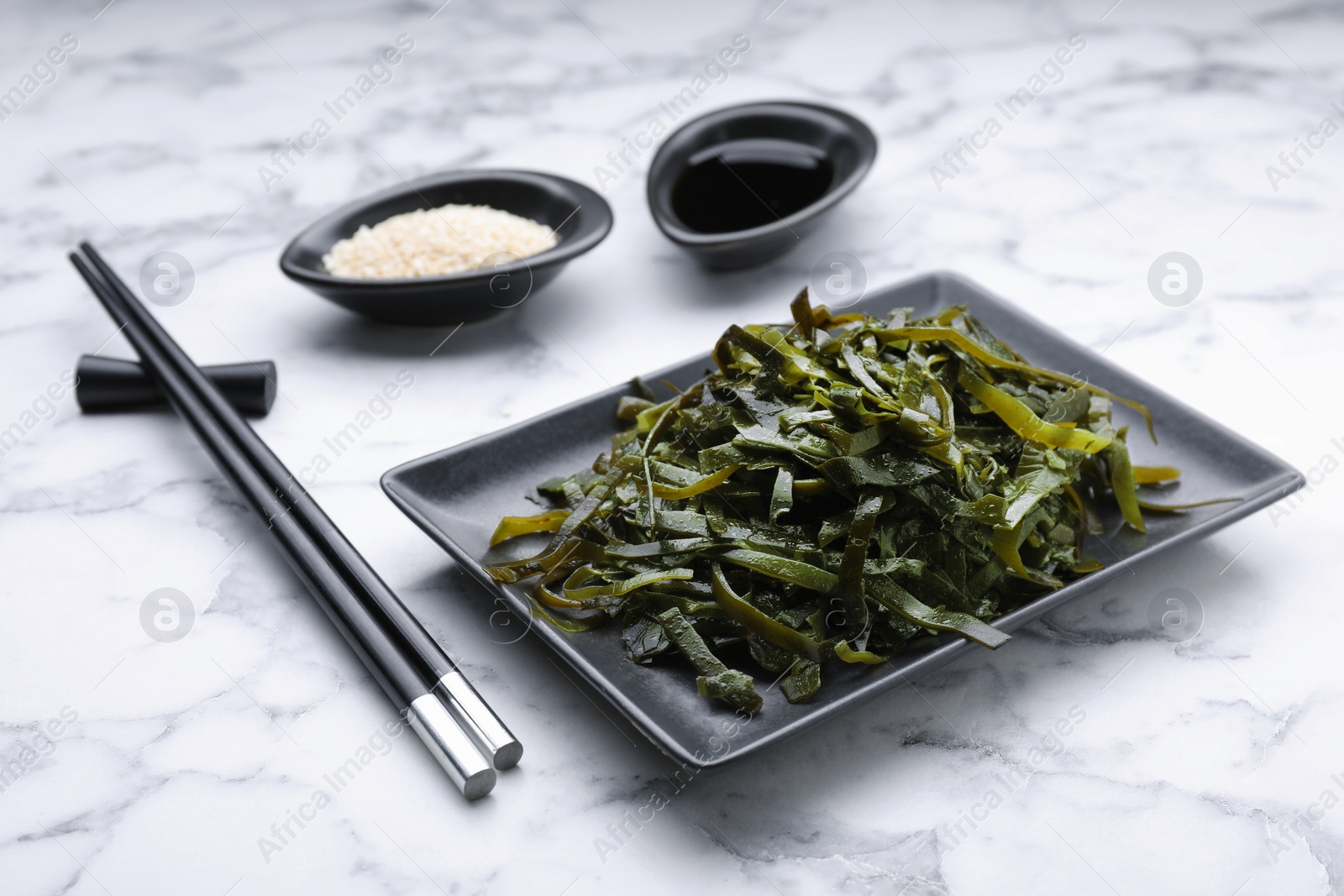 Photo of Fresh laminaria (kelp) seaweed served on white marble table