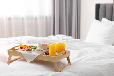 Photo of Tray with tasty breakfast on bed at home, space for text