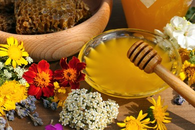 Delicious honey, combs and different flowers on wooden table