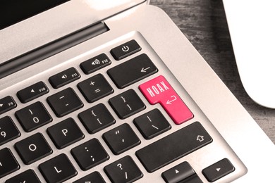Pink button with word Hoax and arrow on laptop keyboard, closeup