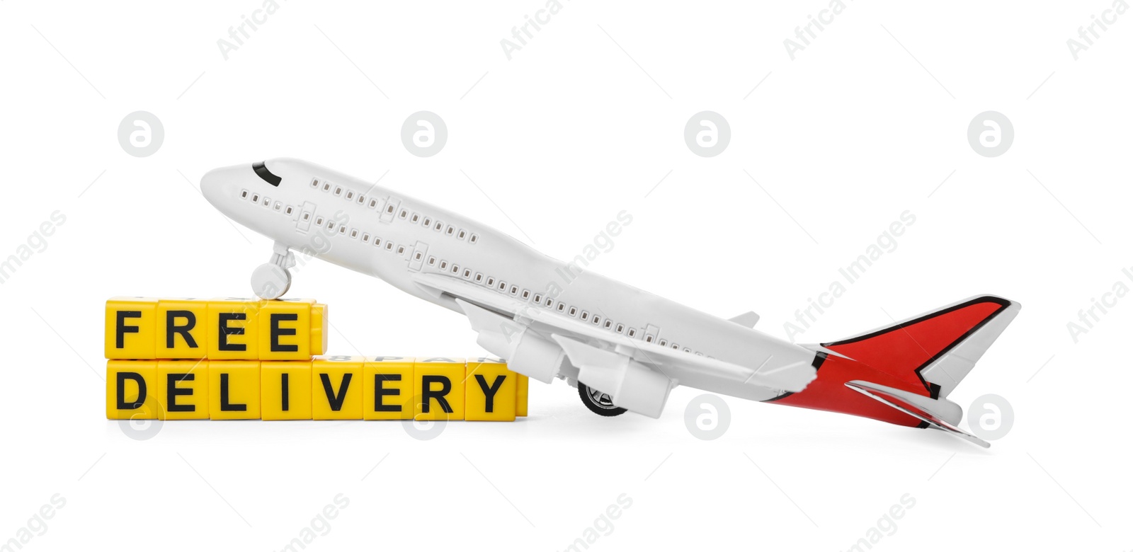 Photo of Toy plane and cubes with words FREE DELIVERY isolated on white. Logistics and wholesale concept