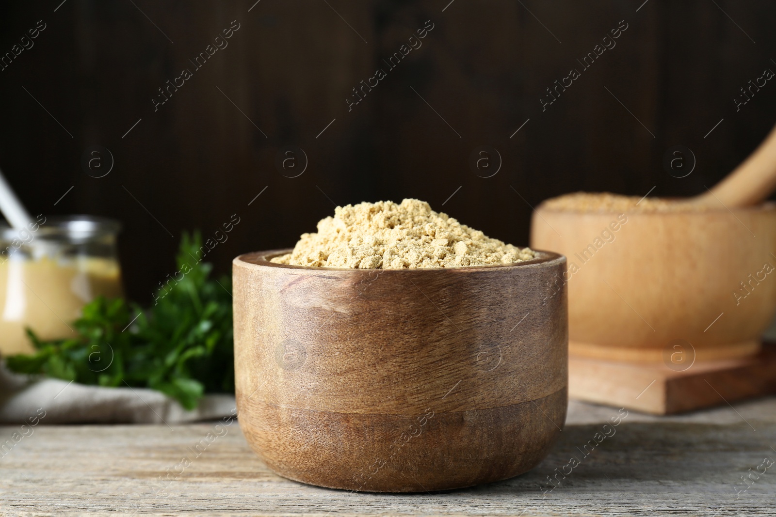 Photo of Bowl of mustard powder on wooden table, closeup