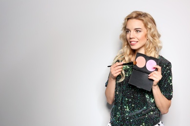 Photo of Beauty blogger with brush and blusher palette on light background