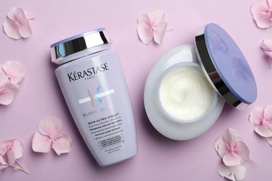 Photo of MYKOLAIV, UKRAINE - SEPTEMBER 07, 2021: Kerastase hair care cosmetic products and hydrangea florets on violet background