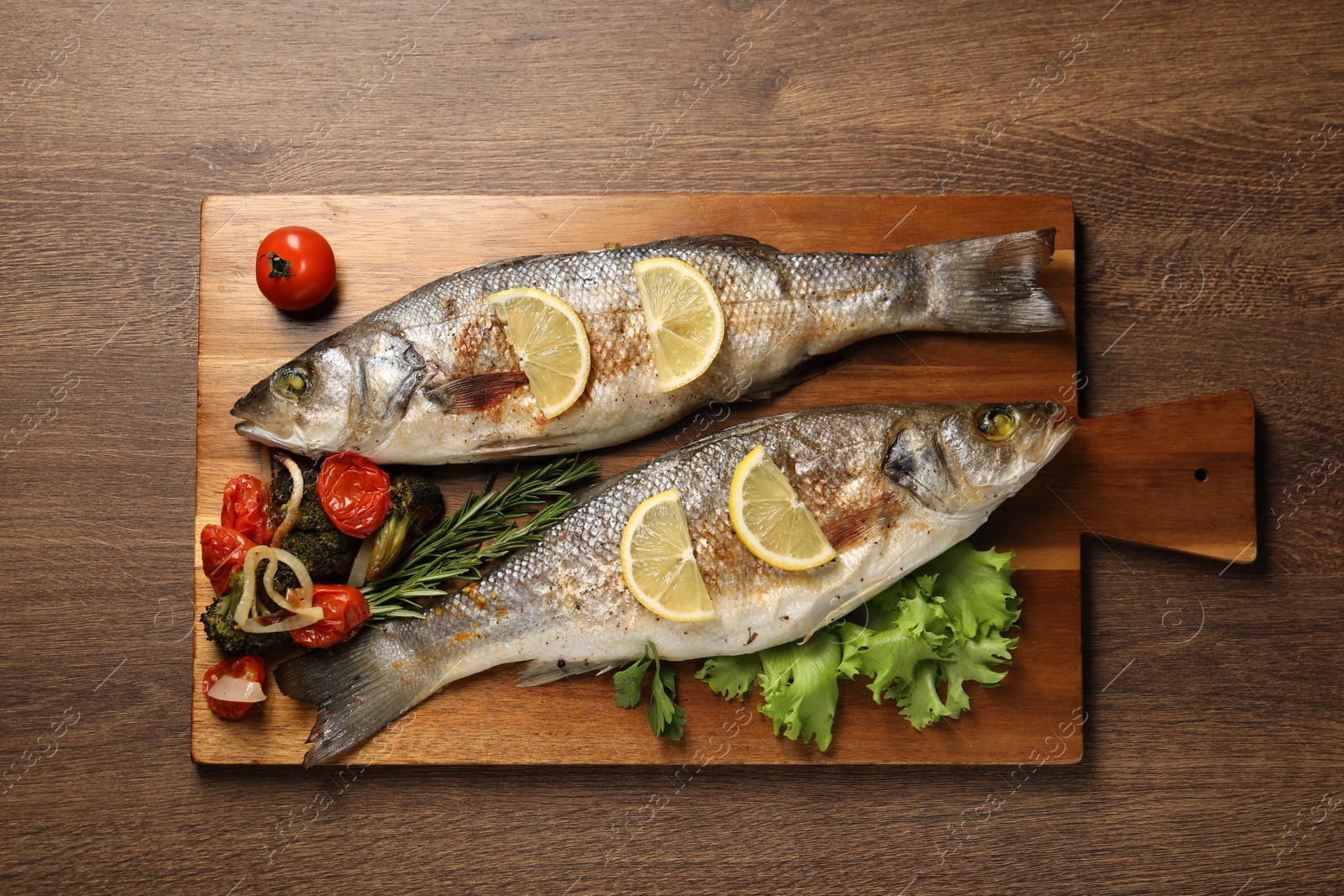 Photo of Delicious baked fish and vegetables on wooden table, top view