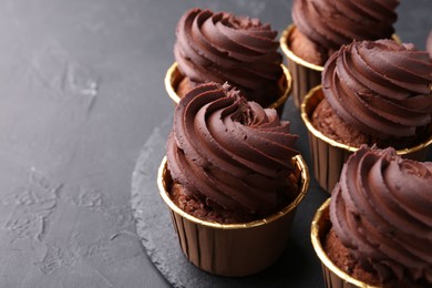 Photo of Delicious chocolate cupcakes on black textured table, closeup. Space for text