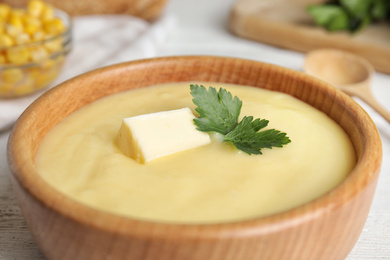 Photo of Delicious corn cream soup in wooden bowl, closeup