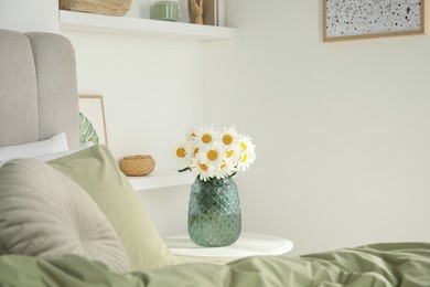 Photo of Bouquet of beautiful daisy flowers on table in bedroom