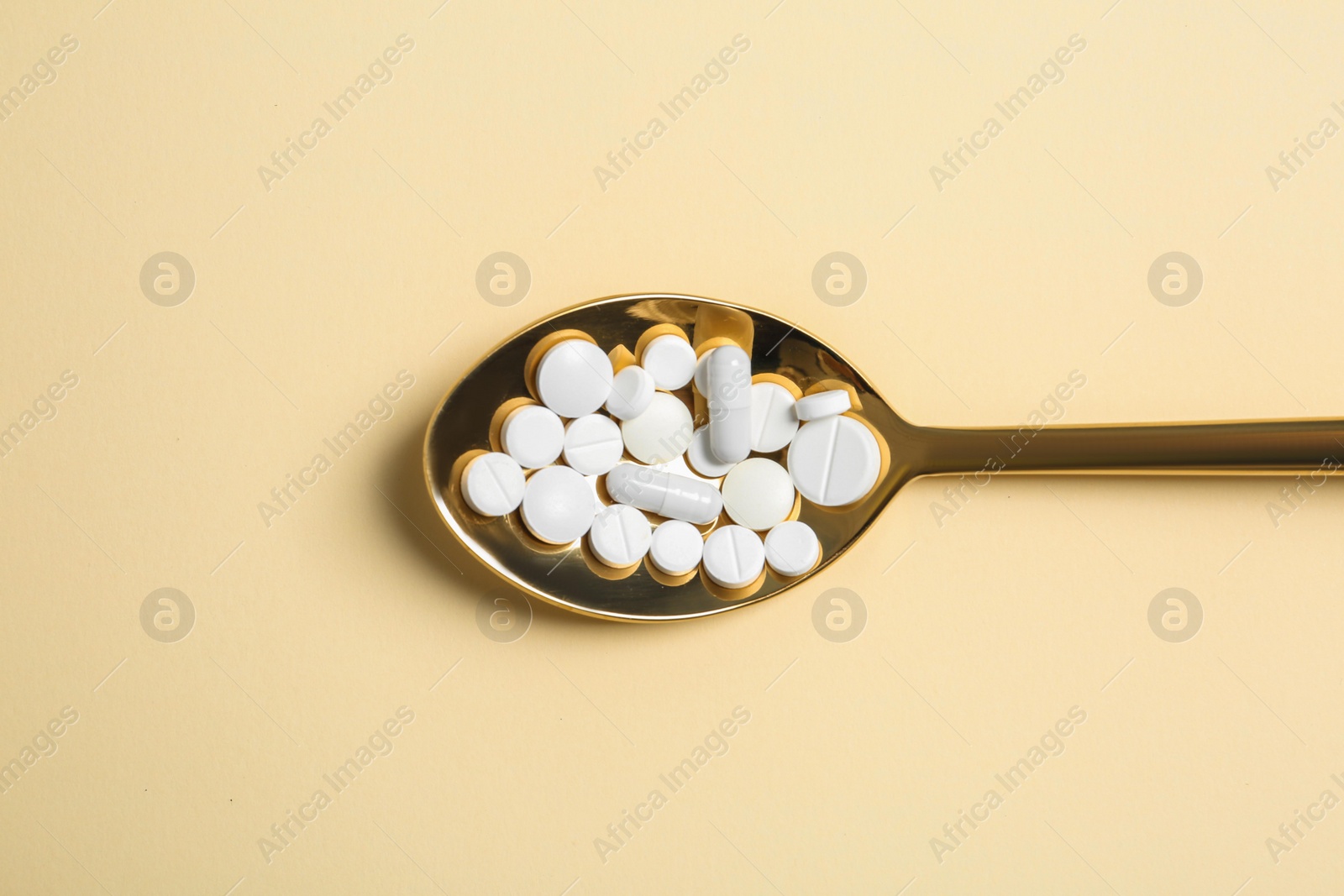 Photo of Spoon of pills on color background, top view