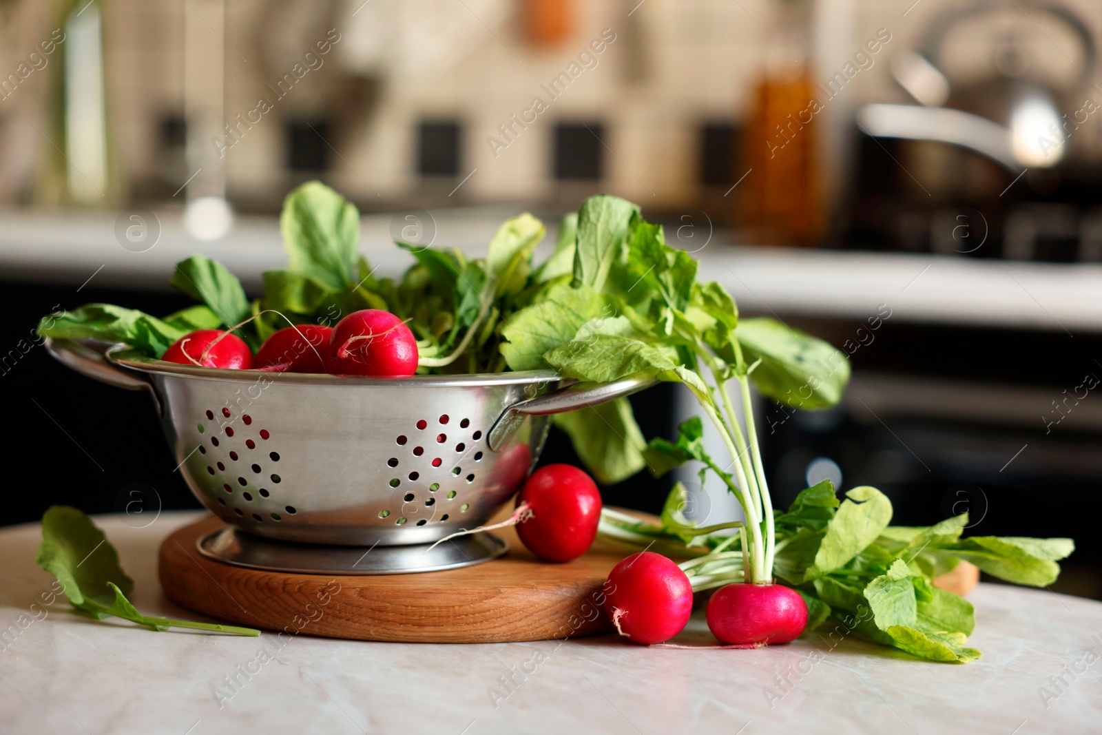 Photo of Metal colander with fresh radishes on white table