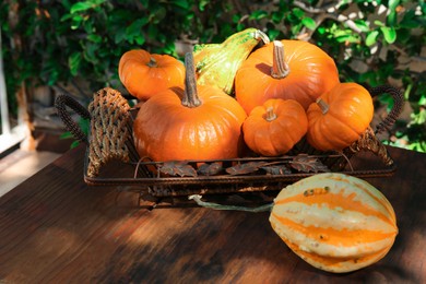 Photo of Different ripe orange pumpkins on wooden table outdoors