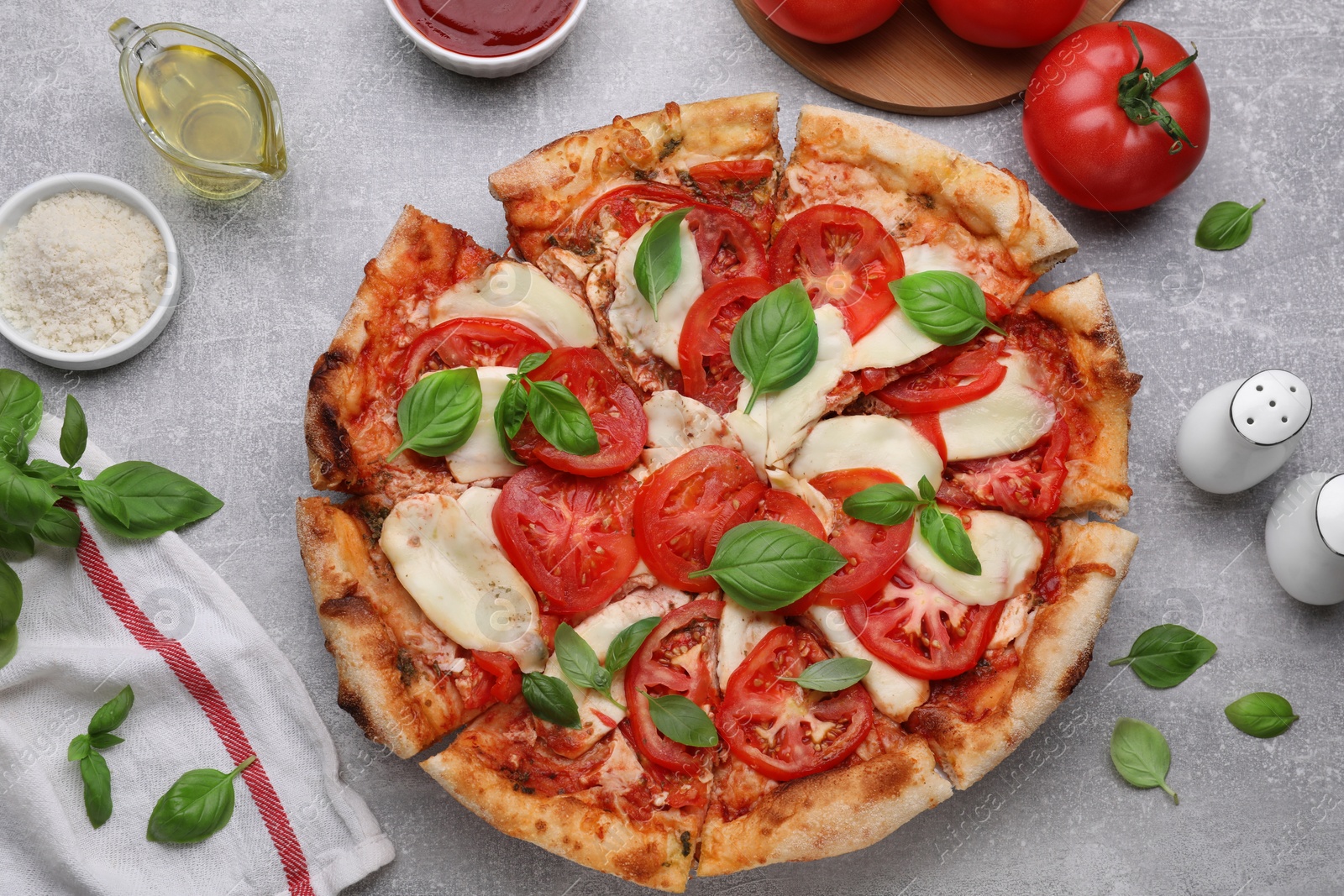 Photo of Delicious Caprese pizza and ingredients on grey table, flat lay