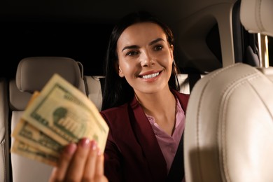 Photo of Young woman with money in modern taxi