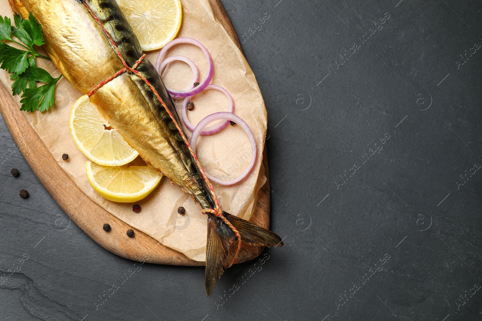 Photo of Tasty smoked fish on black table, top view. Space for text