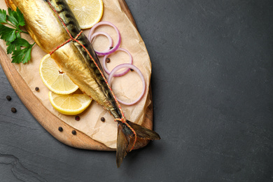 Photo of Tasty smoked fish on black table, top view. Space for text