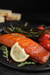 Photo of Delicious cooked salmon with lemon on black table, closeup. Healthy meals from air fryer