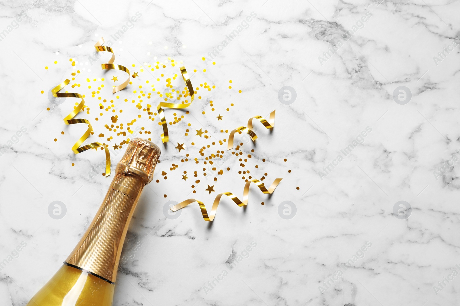 Photo of Flat lay composition with bottle of champagne for celebration on white marble background. Space for text