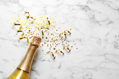 Photo of Flat lay composition with bottle of champagne for celebration on white marble background. Space for text