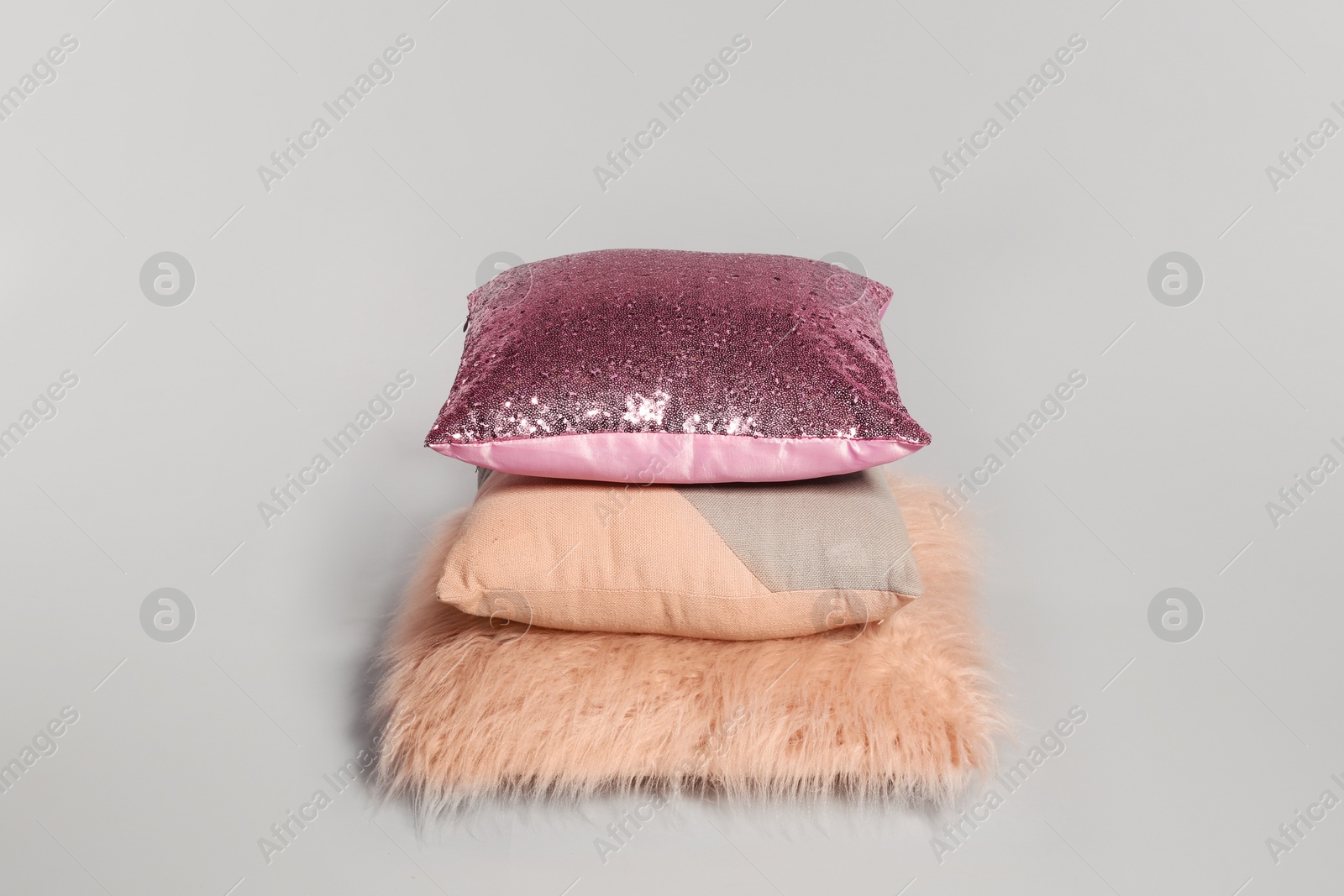 Photo of Stylish decorative pillows stacked on light background