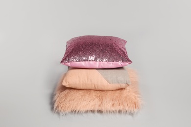 Stylish decorative pillows stacked on light background