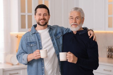 Photo of Happy son and his dad with cups at home