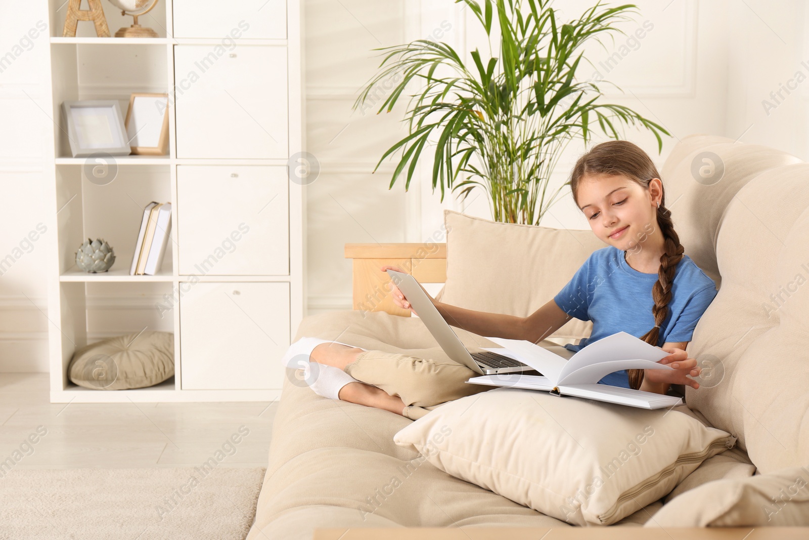 Photo of Girl with laptop and book on sofa at home