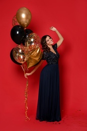 Photo of Happy woman with air balloons on red background. Christmas party