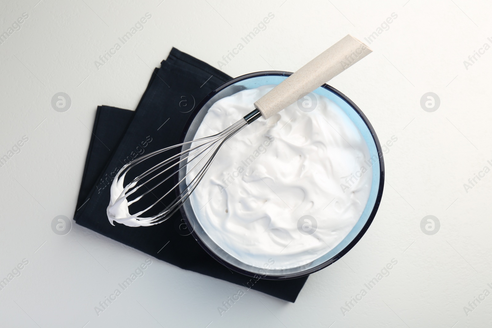 Photo of Bowl with whipped cream and whisk on light background, top view