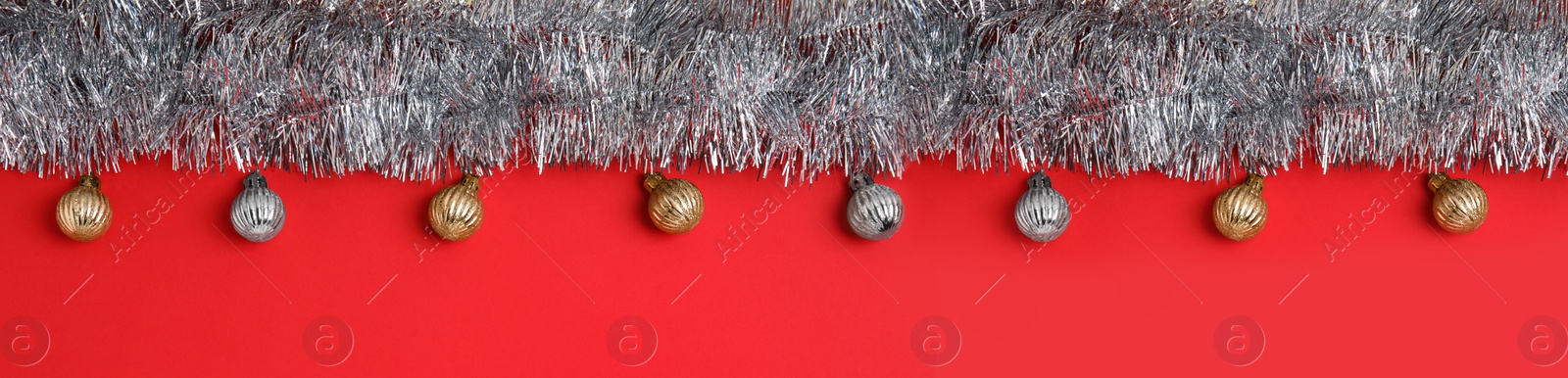 Image of Silver tinsel and Christmas balls on red background, flat lay. Banner design