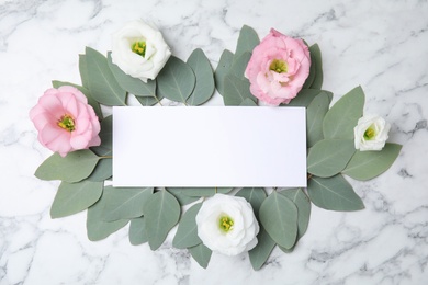 Photo of Fresh eucalyptus leaves, flowers and blank card with space for design on marble background, top view