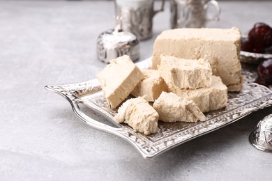 Photo of Pieces of tasty halva served on light grey table, closeup. Space for text