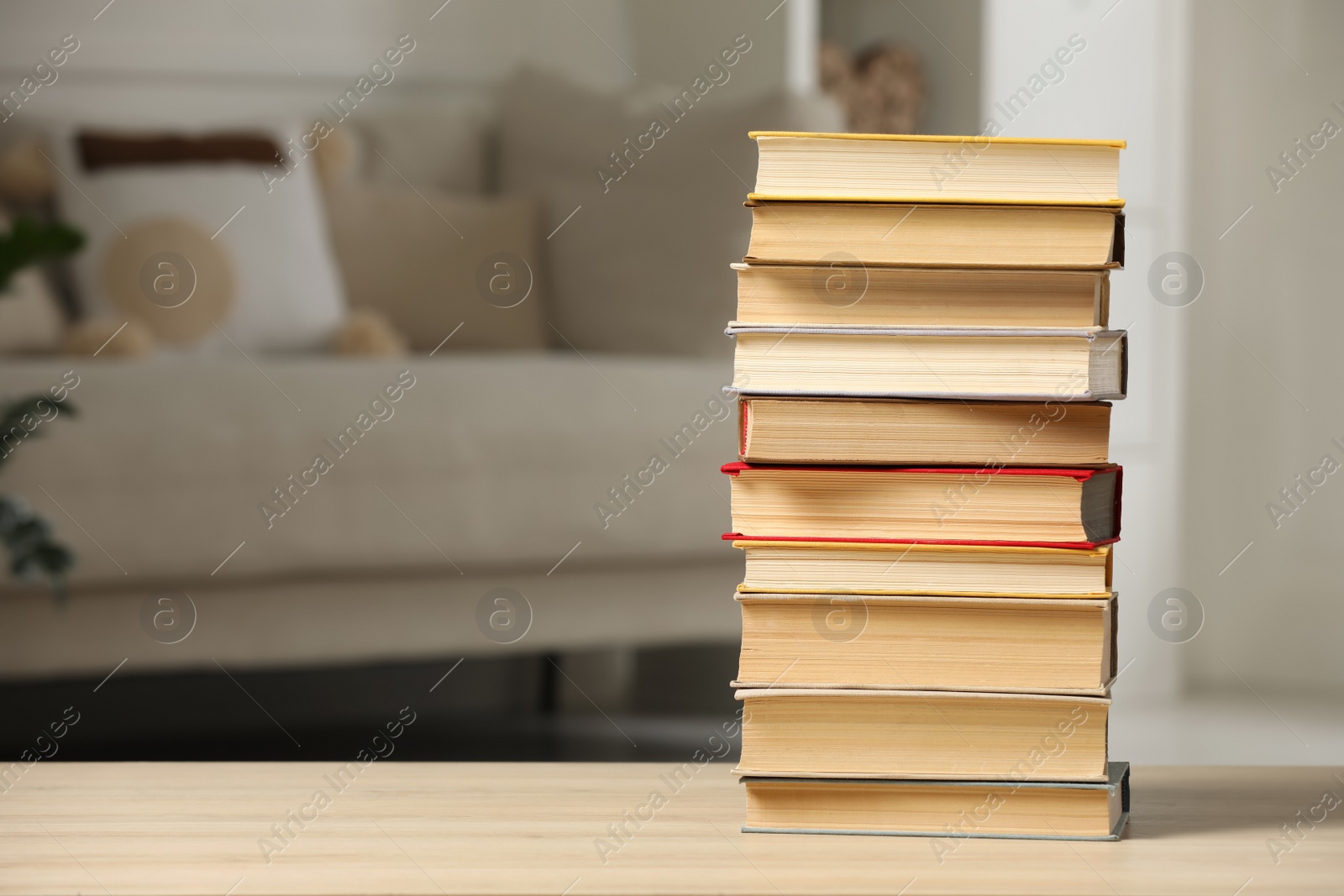 Photo of Stack of books on wooden table in living room, space for text. Home library