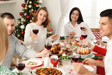 Photo of Happy family with their friends enjoying festive dinner at home. Christmas Eve celebration