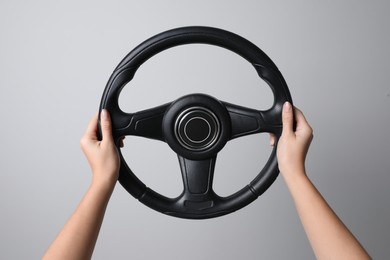 Photo of Woman holding steering wheel on grey background, closeup