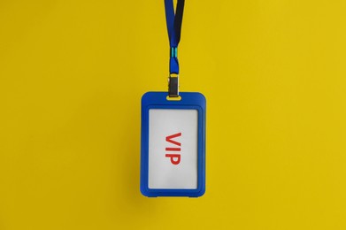 Photo of Blue plastic vip badge hanging on yellow background