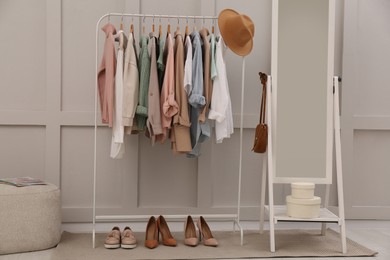 Rack with stylish women's clothes and mirror in dressing room