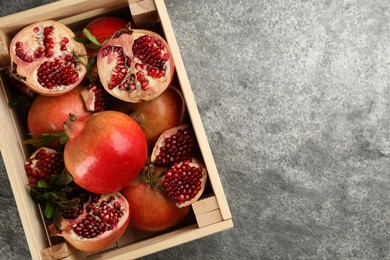 Photo of Delicious ripe pomegranates on grey table, top view. Space for text