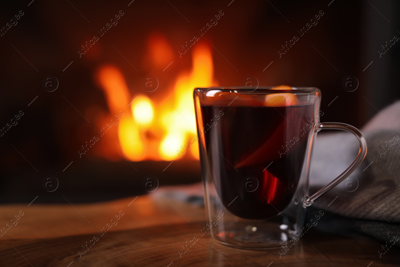 Photo of Tasty mulled wine, plaid and blurred fireplace on background