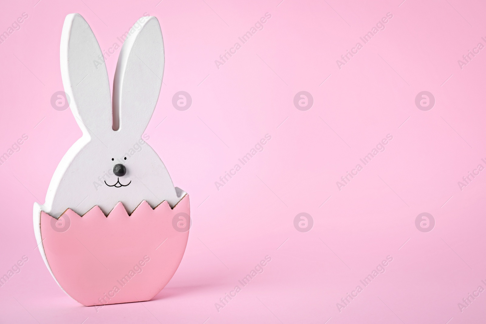 Photo of Easter bunny figure on pink background. Space for text