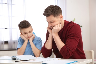 Photo of Dad helping his son with difficult homework assignment in room