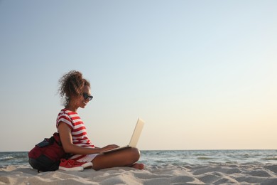 African American woman working on laptop at beach