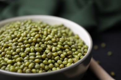 Photo of Bowl with green mung beans on black background, closeup