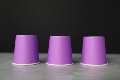 Photo of Shell game. Three purple cups on grey marble table