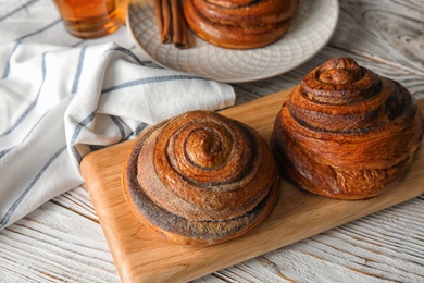 Photo of Wooden board with cinnamon rolls on table