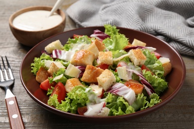 Photo of Delicious fresh Caesar salad on wooden table