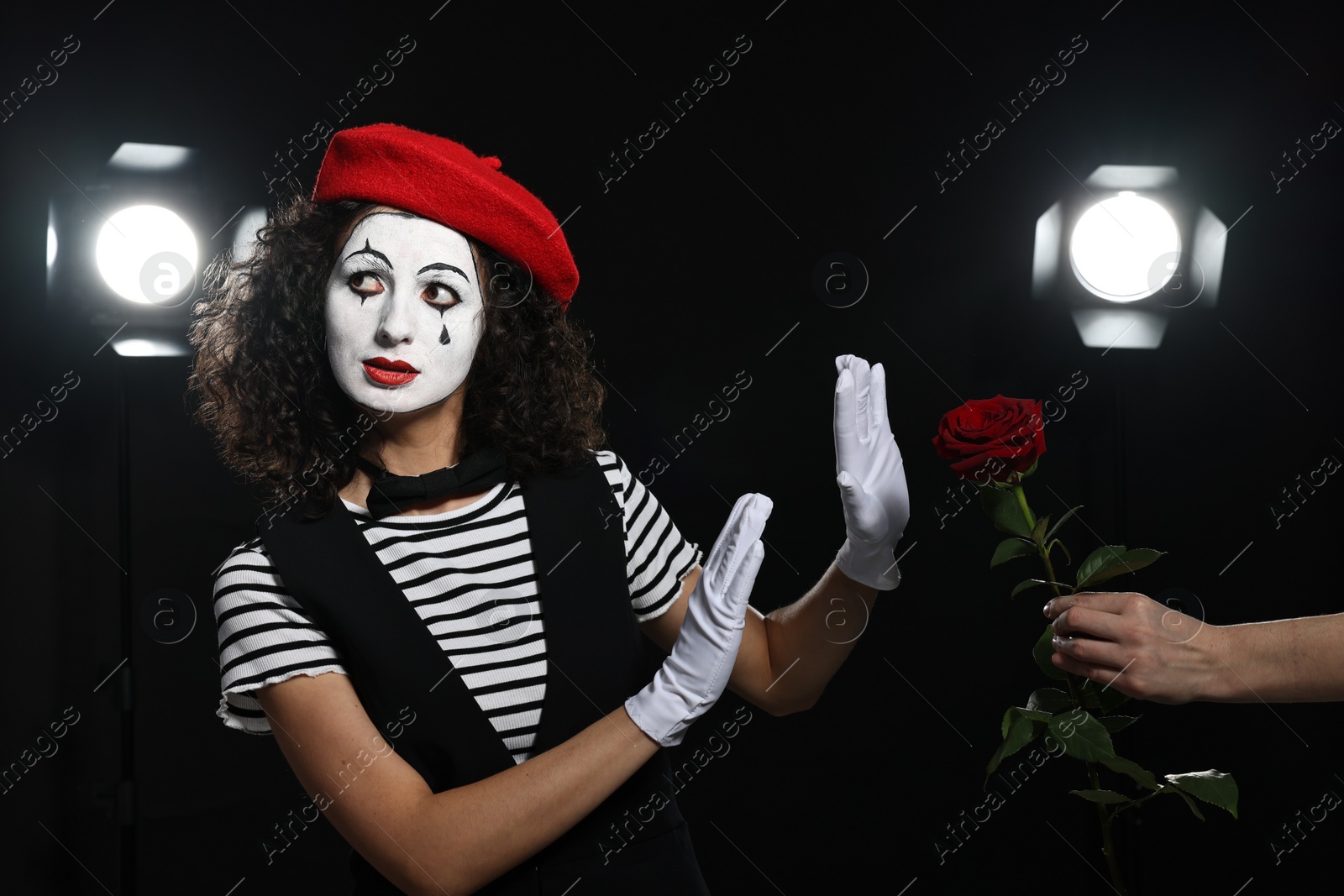 Photo of Man giving red rose to young woman in mime costume on stage